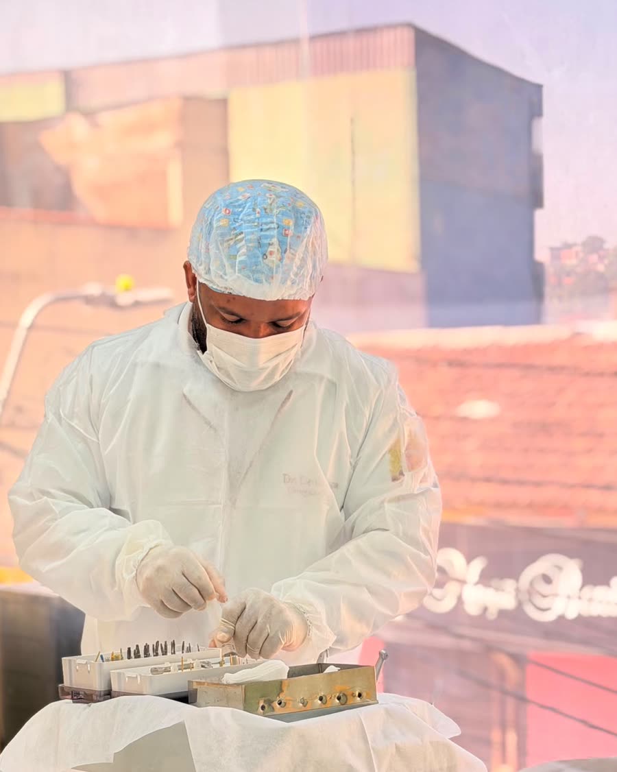 Dentista da Sorrir Bem, com avental cirúrgico, touca e máscara, organiza o kit de instrumentos para implante